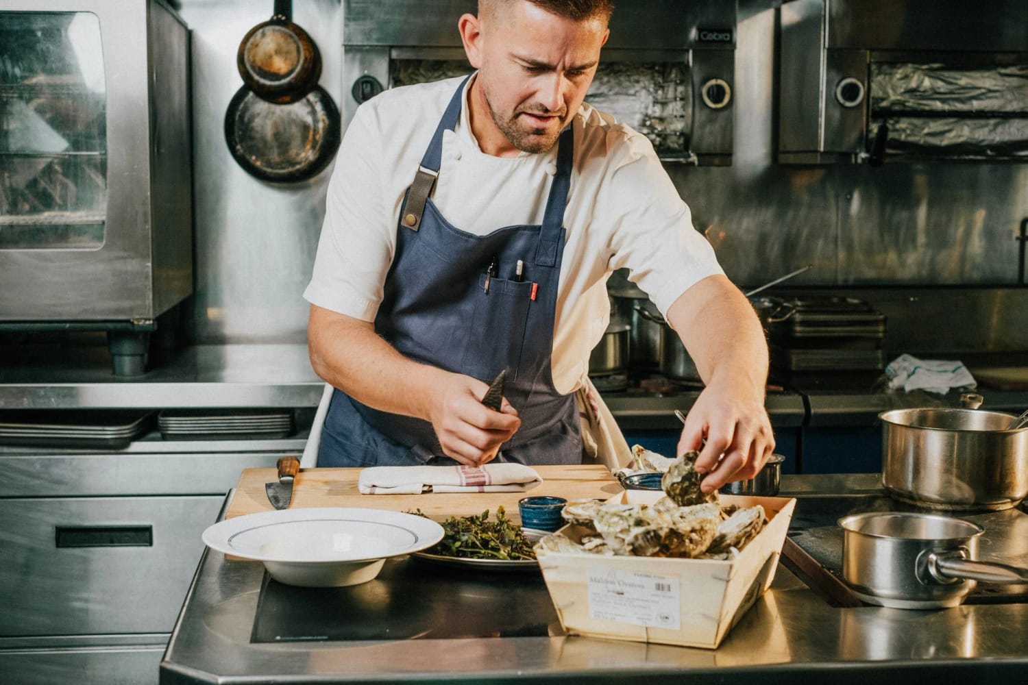 Chef Robert Thompson MBE opening oysters in the kitchen