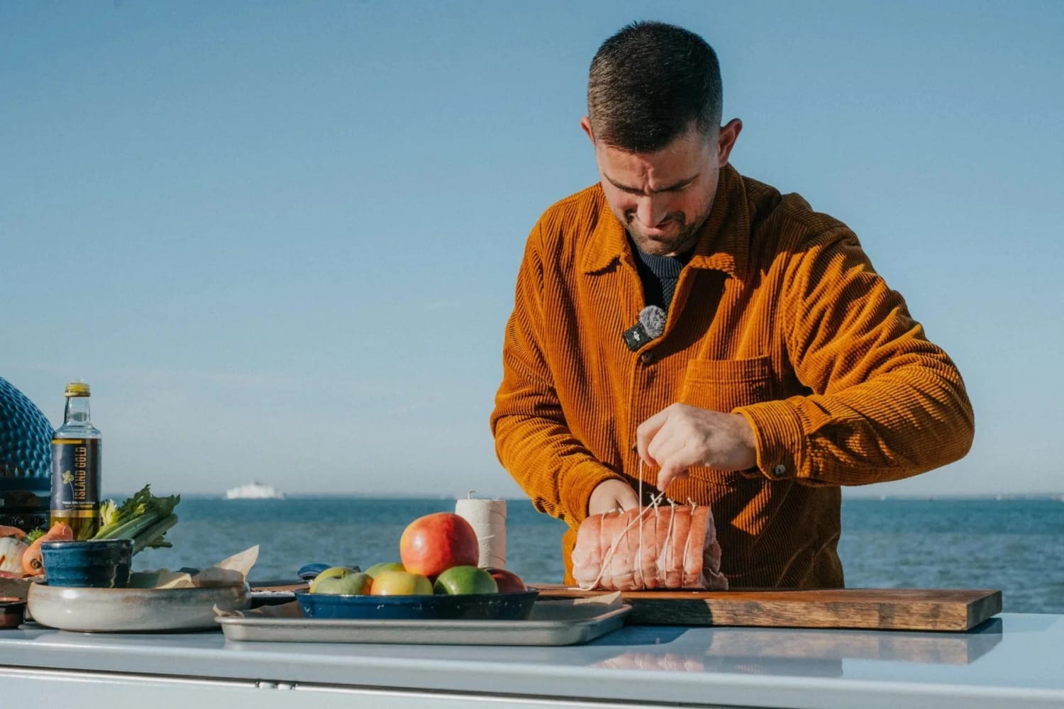 Chef Robert Thompson preparing food at an outdoor kitchen beside the sea