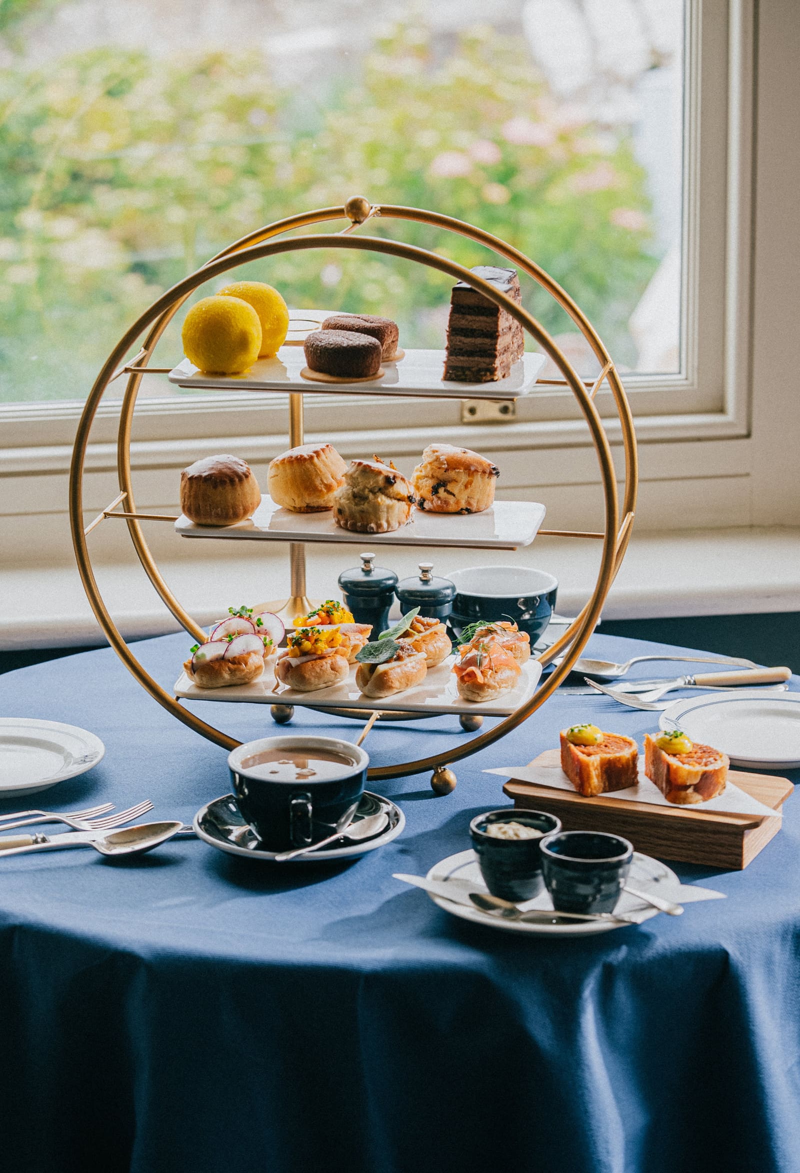 Afternoon tea on a brass stand by the window, on a blue tablecloth