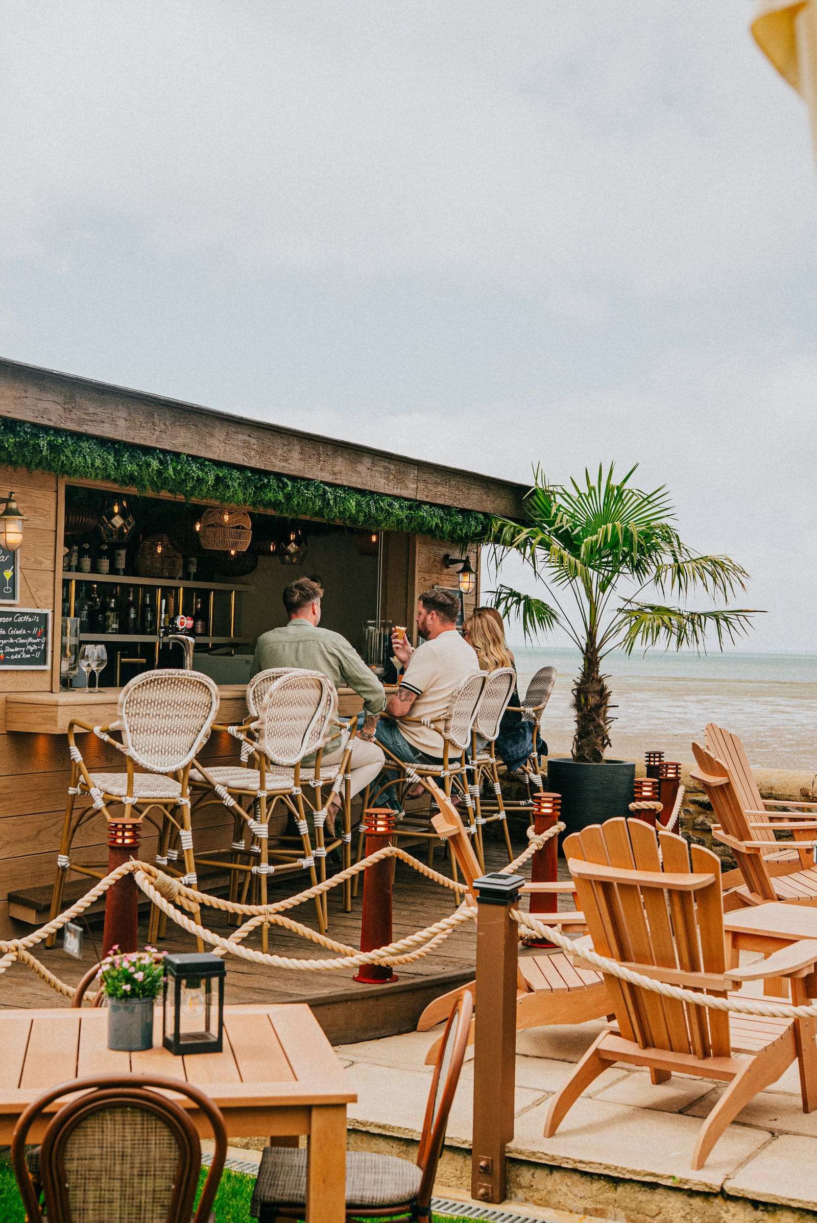 Guests at the garden bar on the terrace, the beach and the Solent beyond