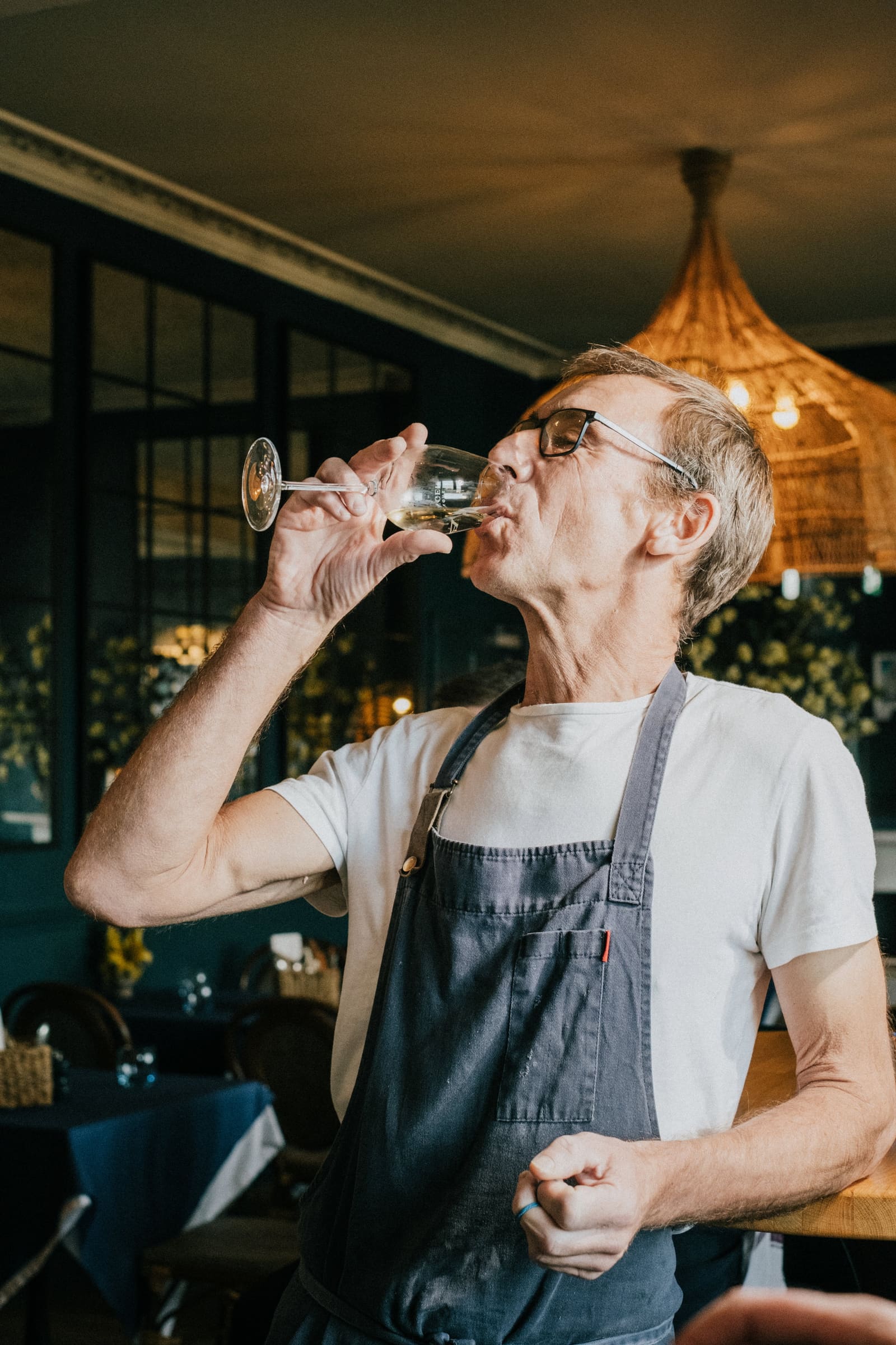 A chef tasting a glass of white wine in the dining room