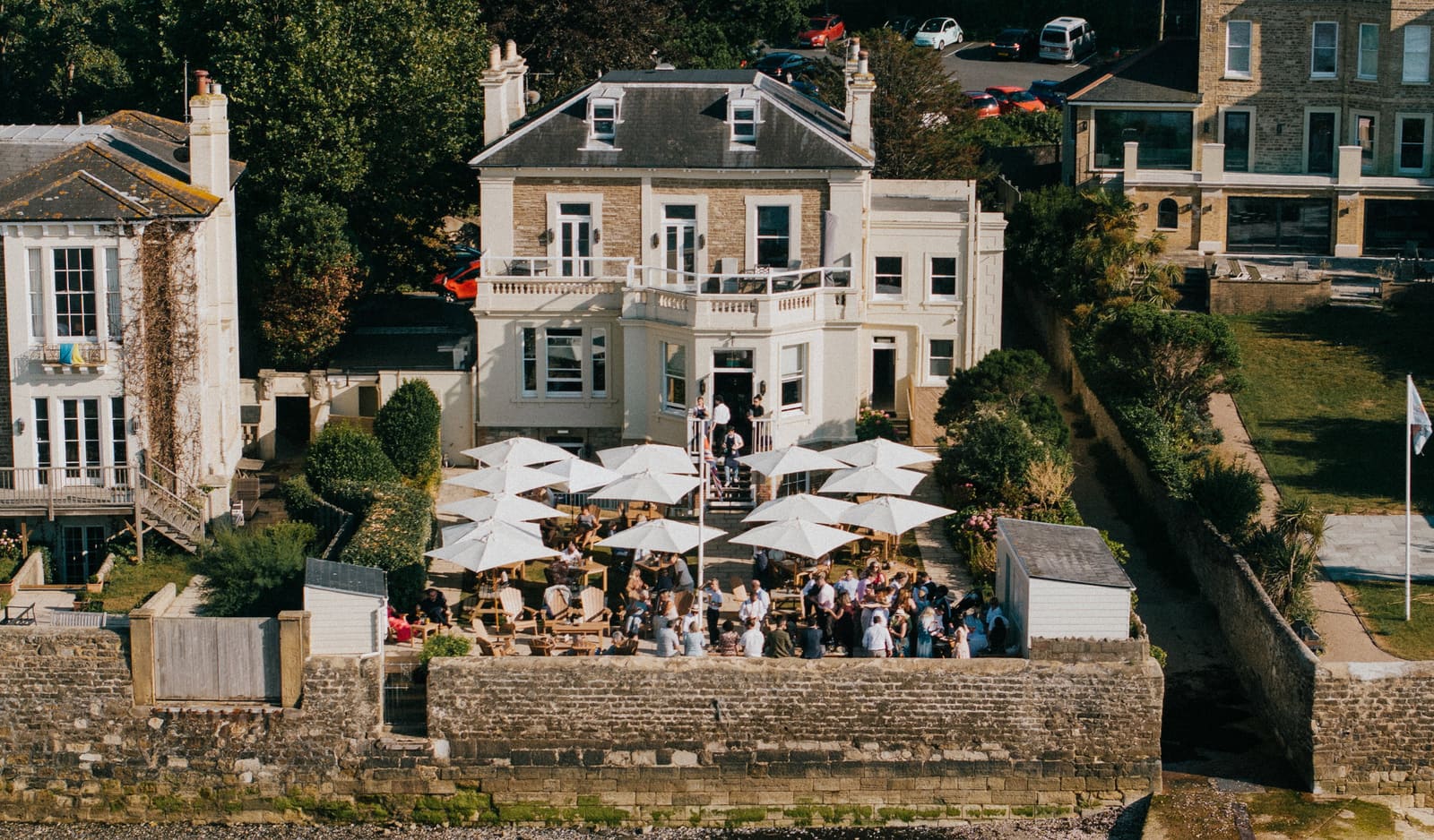Royal Maritime House from the air: the terrace under white parasols, the sea wall and the beach