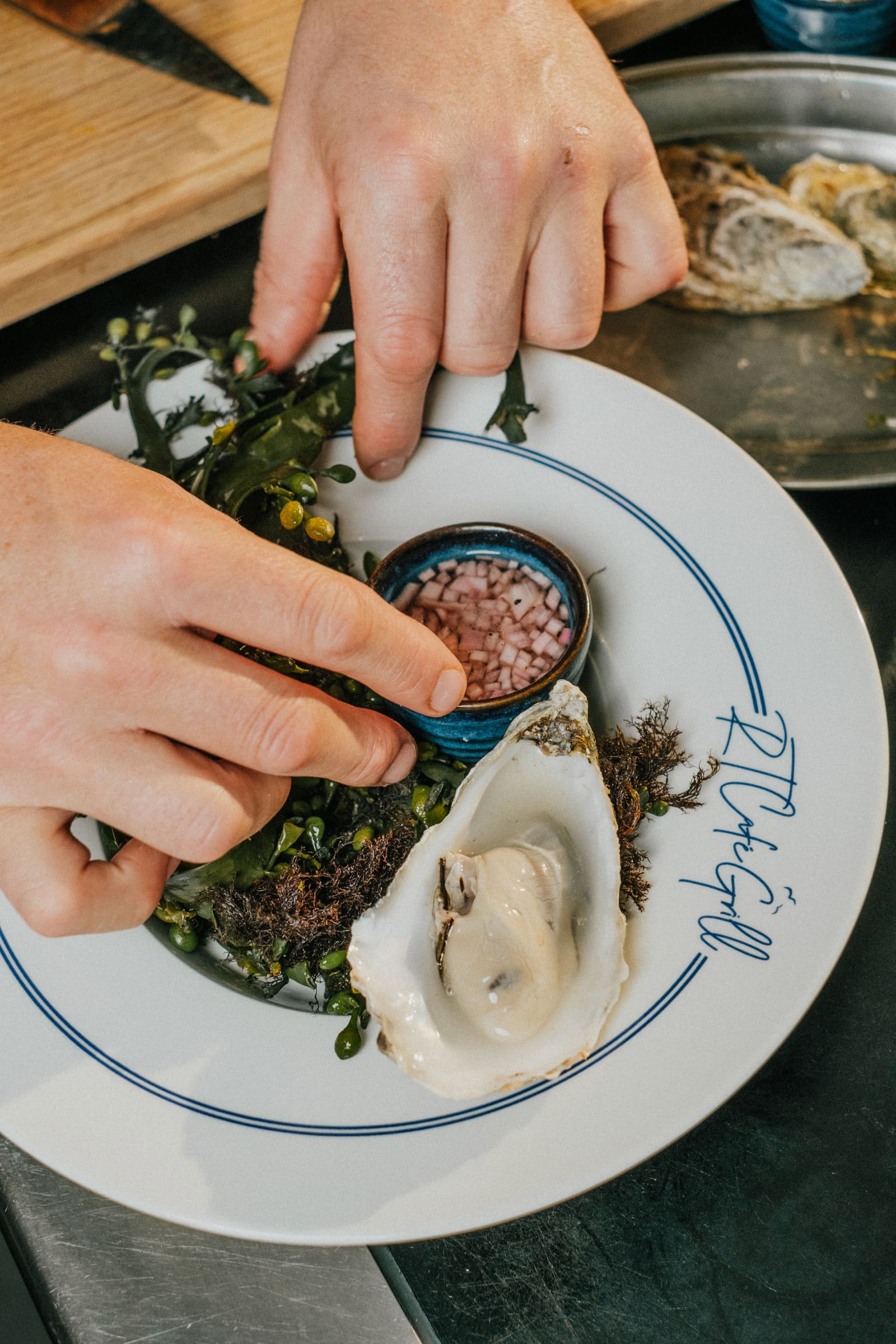 A chef dressing oysters with seaweed