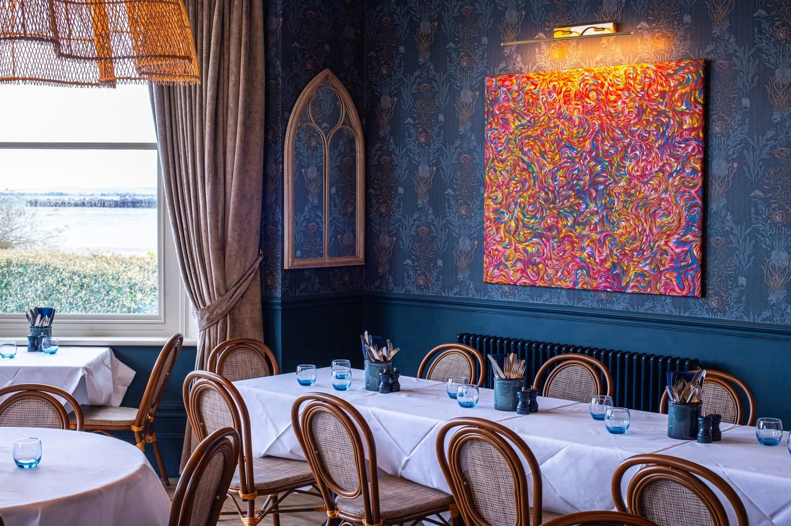 The dining room at RT Café Grill in the evening, tables laid, the Solent through the window